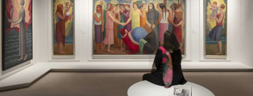 Salle d'exposition Art Déco France avec toiles figuratives éclairées et visiteuse assise, conception lumière Ponctuelle