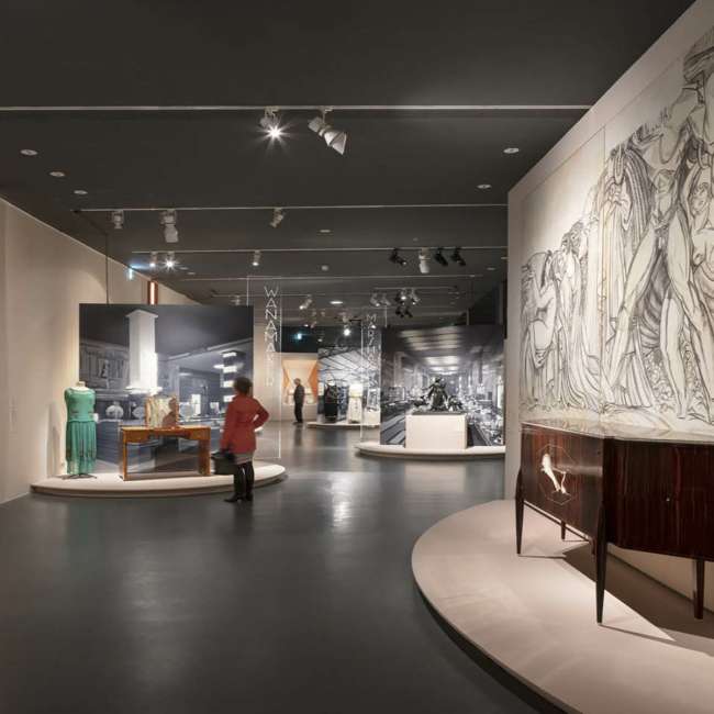 Galerie de l'exposition Art Déco France avec vitrines de mode et grand dessin mural éclairés, conception lumière Ponctuelle