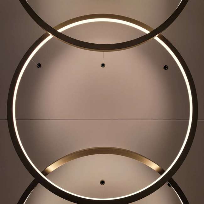 Détail de luminaires circulaires entrelacés au plafond, conception lumière bureaux Paris Ponctuelle