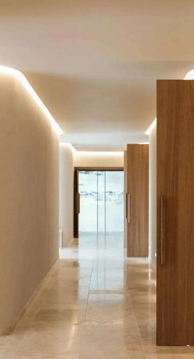 Couloir du Domaine de Verchant avec éclairage indirect corniche et portes en bois, conception lumière Ponctuelle