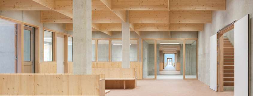Espace commun sous charpente bois lamellé-collé avec bancs intégrés, conception lumière Ponctuelle