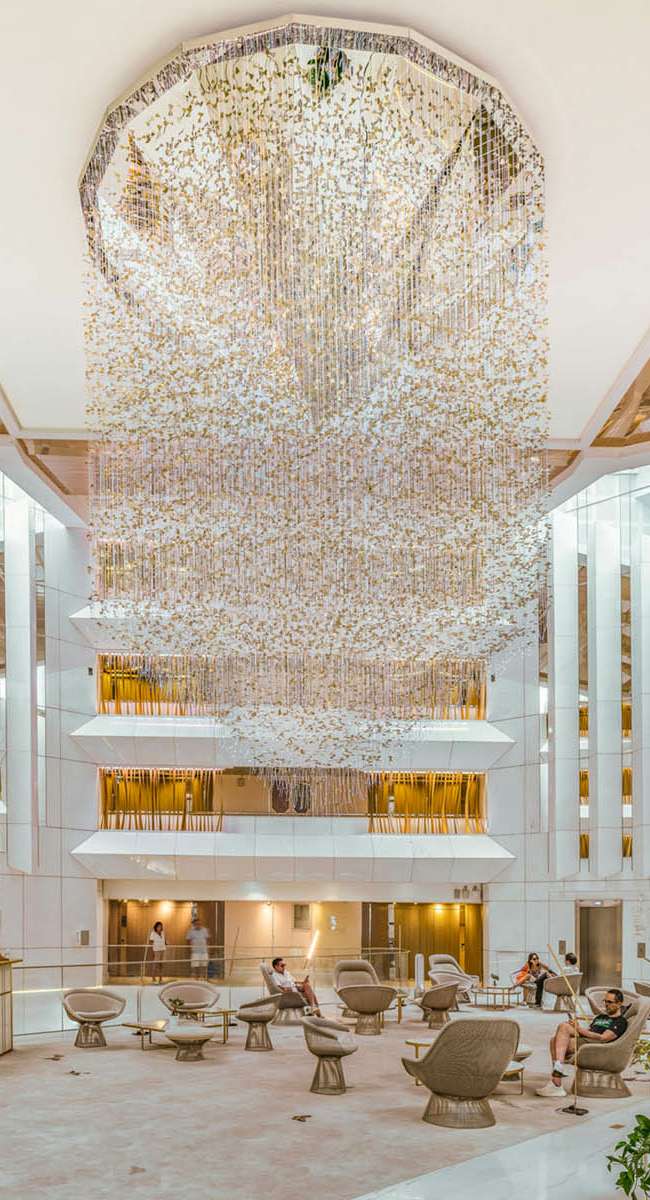 Hall de réception du JW Marriott Cannes avec suspension lumineuse monumentale et atrium sur plusieurs niveaux, conception lumière Ponctuelle