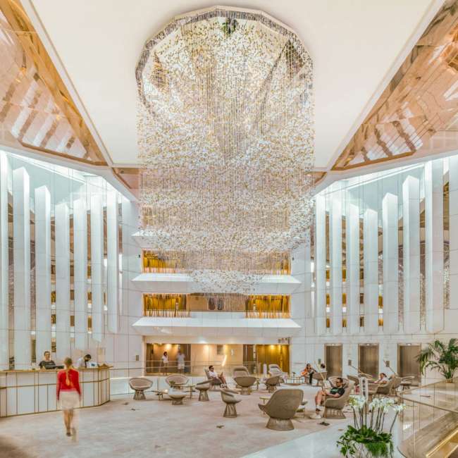 Hall de réception du JW Marriott Cannes avec suspension lumineuse monumentale et atrium sur plusieurs niveaux, conception lumière Ponctuelle