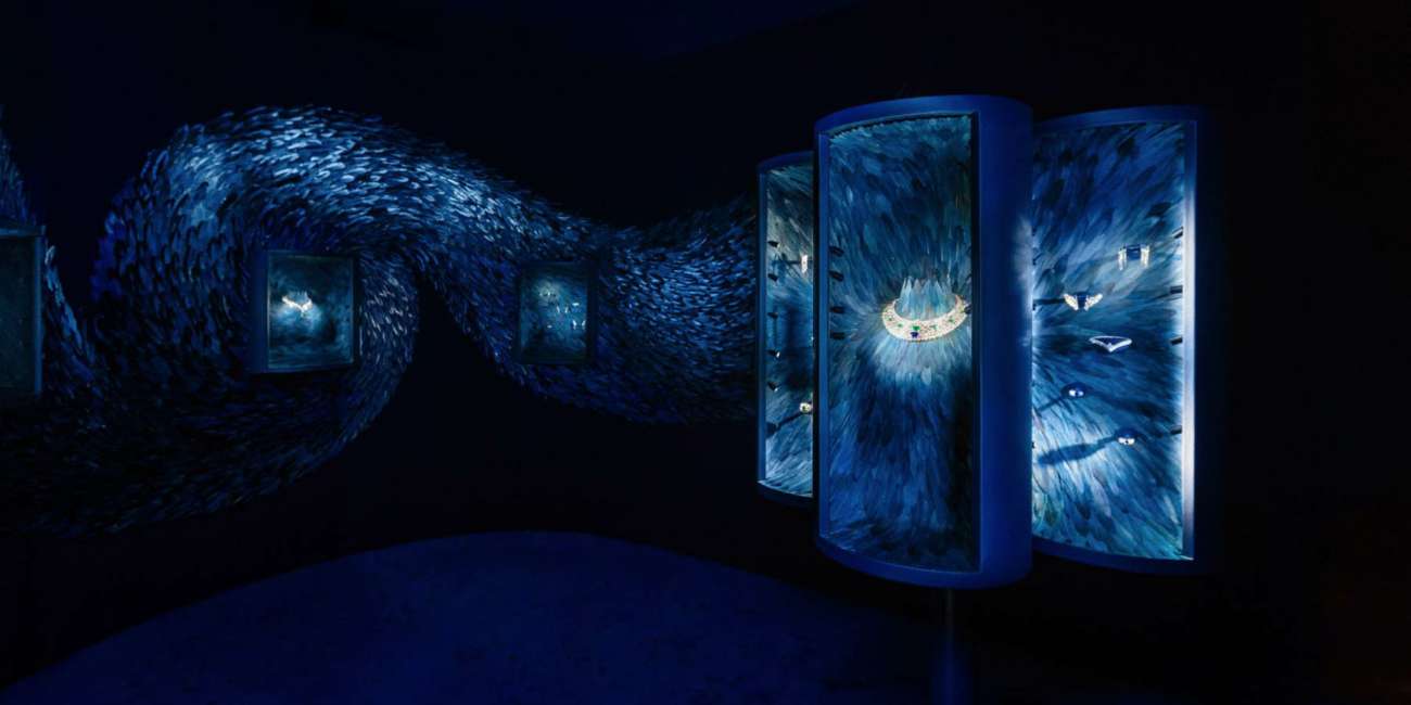 Vitrines de joaillerie intégrées à une fresque de plumes bleues en mouvement, mise en lumière Louis Vuitton Marrakech