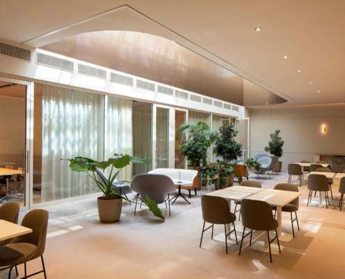 Espace de restauration avec verrière courbe et végétation, mise en lumière Ponctuelle