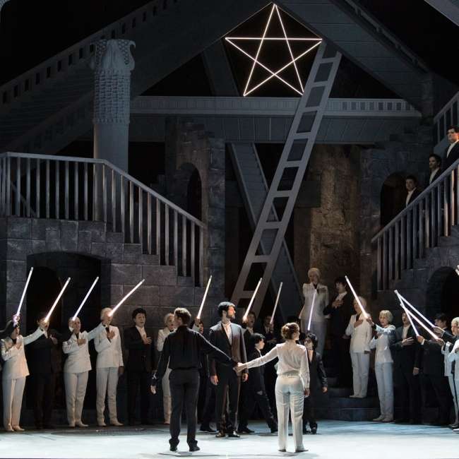 Chorus raising luminous sabres around Tamino and Pamina, stone set beneath a glowing five-pointed star, The Magic Flute, Marseille Opera, lighting design by Ponctuelle