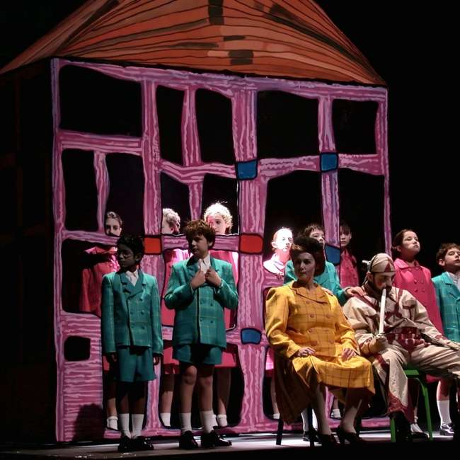 Chœur d'enfants en uniformes verts et roses devant une maison au dessin naïf rose, Wozzeck, Opéra de Nantes, conception lumière Ponctuelle